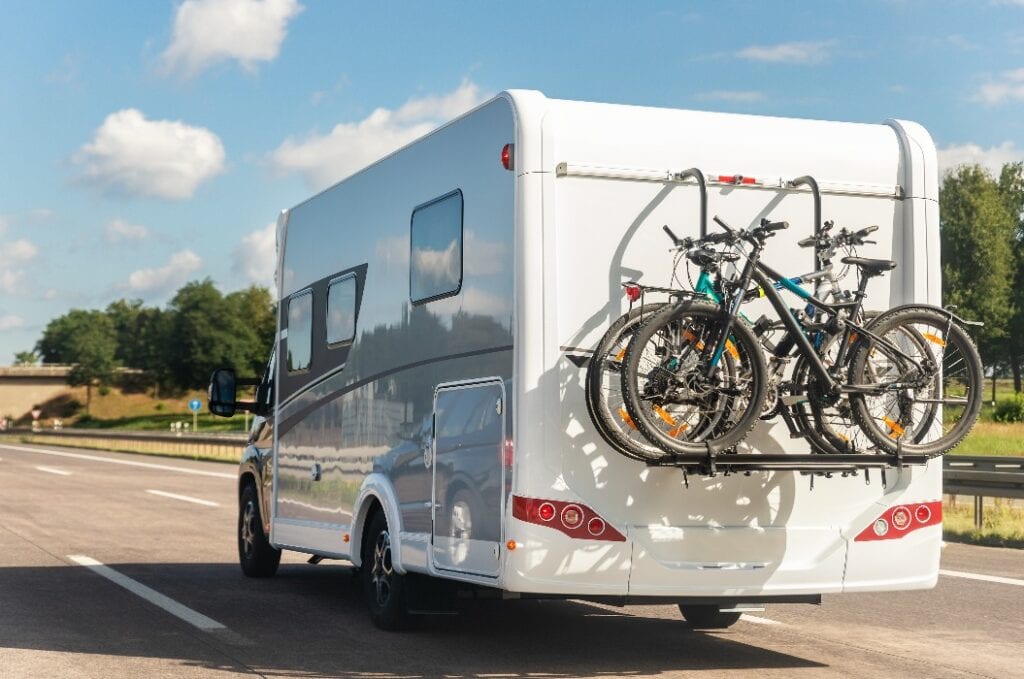 Reisemobil mit Fahrrädern auf Träger fährt auf einer Autobahn