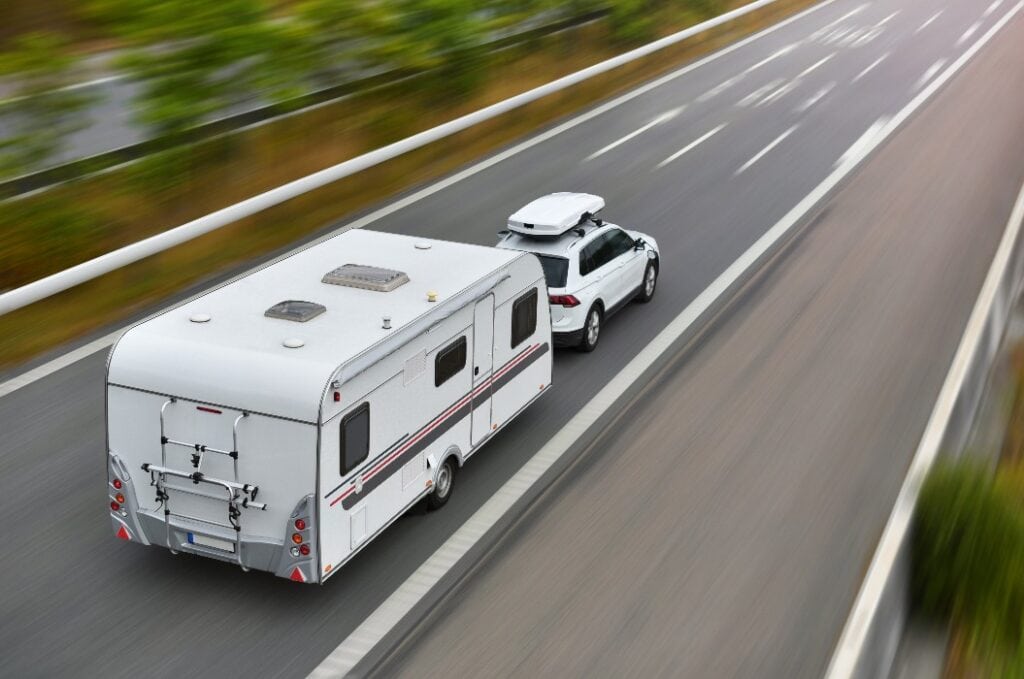 SUV mit Dachbox zieht Caravan dank Fahrsicherheitstraining sicher auf einer zweispurigen Straße