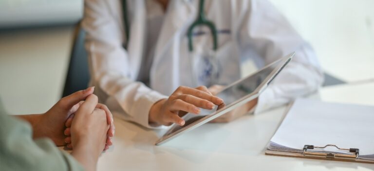 Aufnahme eines Arztes, der einem Patienten die Untersuchungsergebnisse auf einem Tablet zeigt