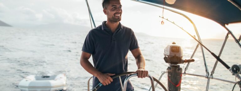 Lächelnder junger Mann als Steuermann auf einem Segelboot